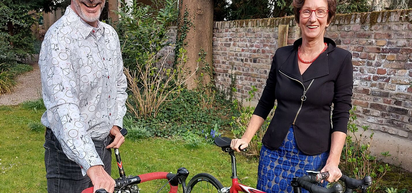 Zwei Personen - Axel Fell und Annette Quaedvlieg - mit Rennrädern im Garten