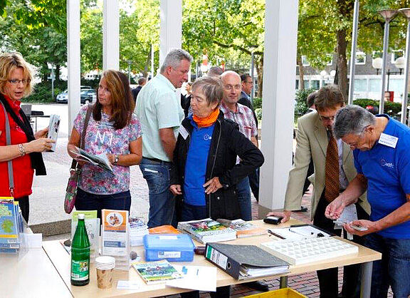Viele Leute an einem Tisch stehend im Gespräch