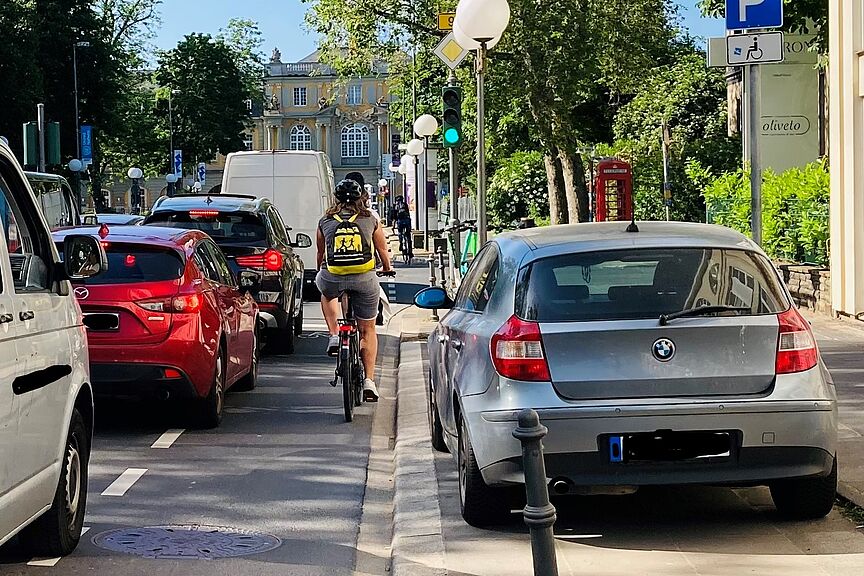 Foto vom Autostau auf der Adenauerallee mit einem an den Rand gedrückten Radfahrenden