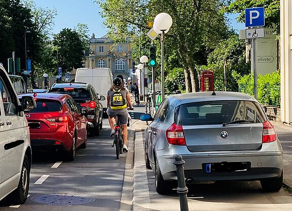 Foto vom Autostau auf der Adenauerallee mit einem an den Rand gedrückten Radfahrenden