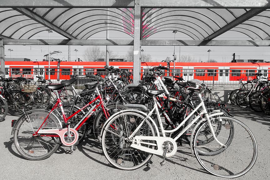 Zug im Hintergrund davor viele abgestellte Fahrräder auf dem Bahnsteig