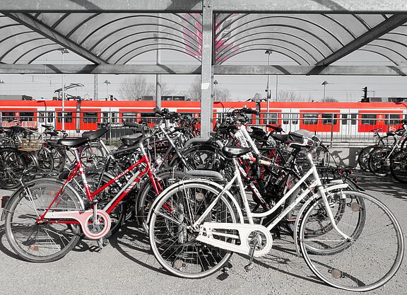 Zug im Hintergrund davor viele abgestellte Fahrräder auf dem Bahnsteig