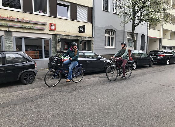 Bild: zwei Personen auf dem Rad sind unterwegs zur Schule